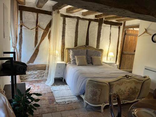 a bedroom with a bed and a chair in it at Le Grand Faubourg les Gîtes Ecurie et La Faïencerie in Lorris