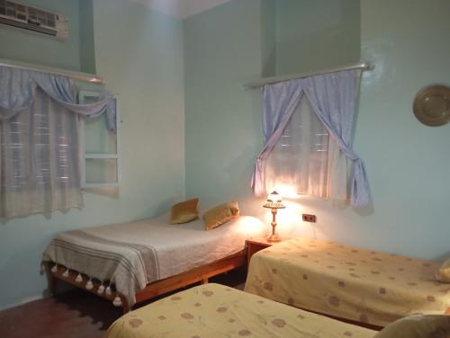 Cette chambre comprend deux lits, une lampe et des fenêtres. dans l'établissement auberge souktana, à Taliouine