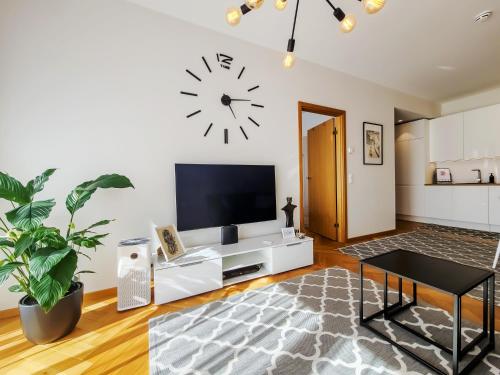 sala de estar con TV y reloj en la pared en Rotermann City Apartments Roseni en Tallin
