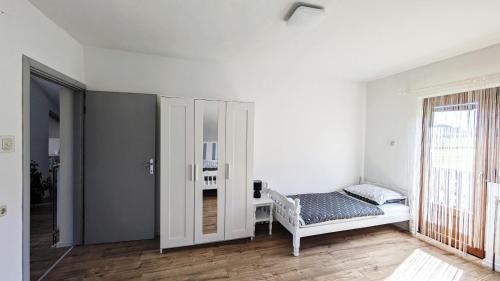 a white room with a bed and a window at Guest House Gacka Rogić in Otočac