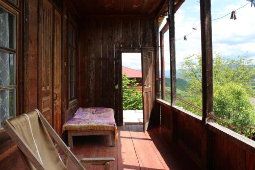 a porch of a house with a bench and windows at Chogovadze's Guest House in K'vemo Zhoshkha