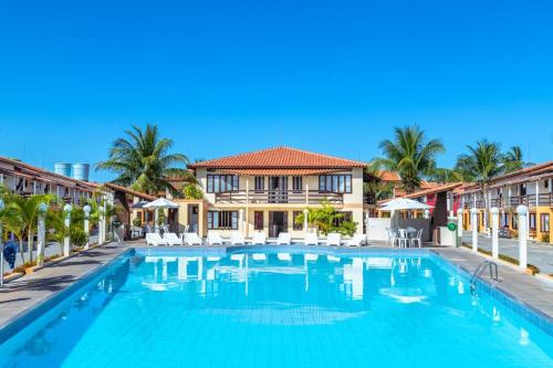 una piscina en un complejo con palmeras en Apto Duplex Village, en Porto Seguro