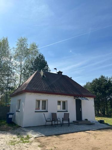 una casa blanca con tres sillas delante en Domek letniskowy, en Skępe