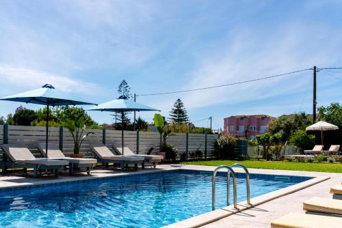 a swimming pool with lounge chairs and umbrellas at Memories Apartments in Laganas