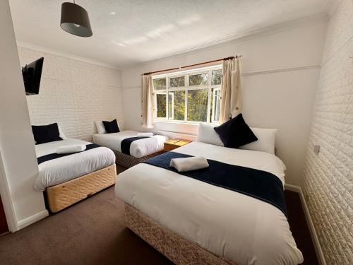 a room with two beds and a window at High Trees Guest House Gatwick in Hookwood