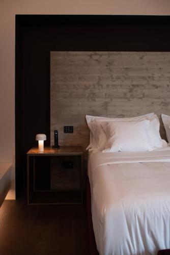 a bedroom with a white bed and a nightstand with a candle at Le Cattedrali Relais by Laqua Collection in Asti