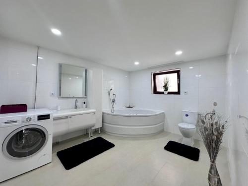 La salle de bains blanche est pourvue d'une baignoire et d'un lave-linge. dans l'établissement Casa Señora, 