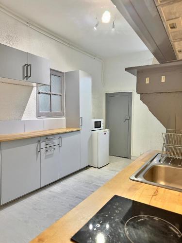 une cuisine avec des armoires blanches et un évier dans l'établissement WonderHost, la Suite de Margot en hypercentre, à Pau