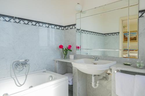 a bathroom with a sink and a tub and a mirror at Sea View Villa Taormina in Taormina