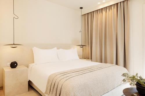 a bedroom with a white bed and a window at Doryssa Method Hotel in Pythagoreio