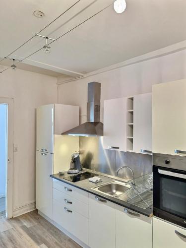 une cuisine avec des armoires blanches et un évier dans l'établissement WonderHost, les volumes de Margot en hypercentre, à Pau