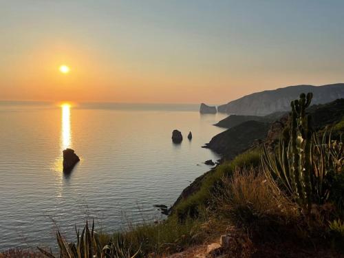 a sunset over a body of water with rocks at La Maison Apache Gonnesa Cod IUN: R8196 in Gonnesa