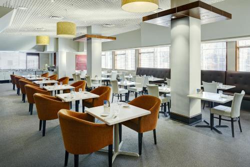 een eetkamer met tafels, stoelen en ramen bij Willis Wellington Hotel in Wellington