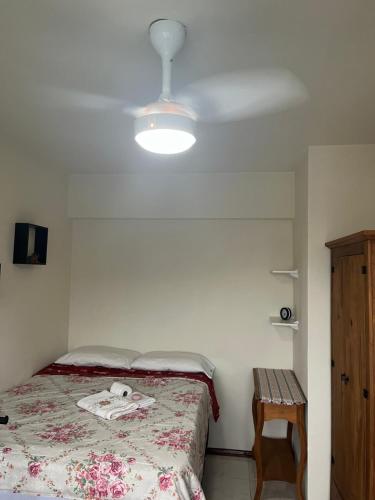 ein Schlafzimmer mit einem Bett, einer Lampe und einem Tisch in der Unterkunft AP Abdon Central Temporada in Joinville