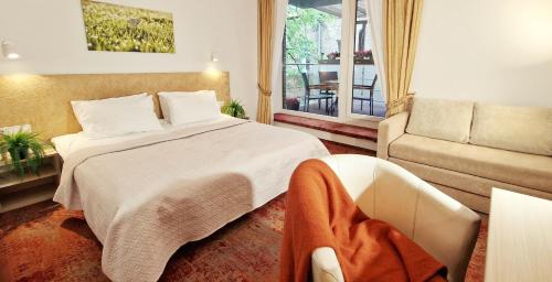 um quarto com uma cama, um sofá e uma janela em Vivulskis Apart-Hotel em Vilnius