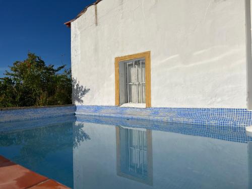 a building with a window next to a swimming pool at Qta Casa Seleiras - Guest House in Évora