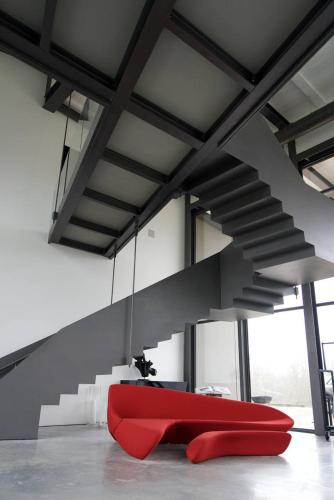 a red couch in a room with stairs at Le Cattedrali Relais by Laqua Collection in Asti