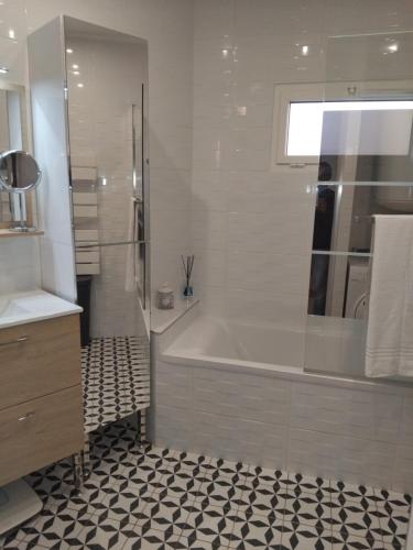 une salle de bain blanche avec une baignoire et un lavabo dans l'établissement Le cosy de Noisy, à Noisy-le-Sec