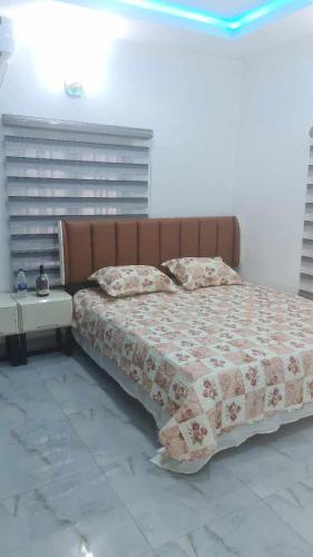 MoniyaにあるIBADAN LUXURY APARTMENTのベッドルーム1室(ブラウンのヘッドボード付きの大型ベッド1台付)