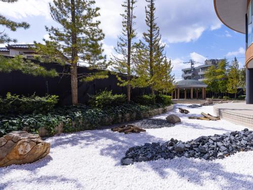 a garden with rocks and trees and a house at APA Hotel & Resort Kaga Katayamazu Onsen Kasuikyo in Kaga