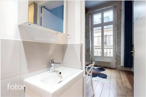 une salle de bain blanche avec un lavabo et un miroir dans l'établissement Chez Gustave: CLIM Calm,Saint Paul Marais, 2Guests, à Paris