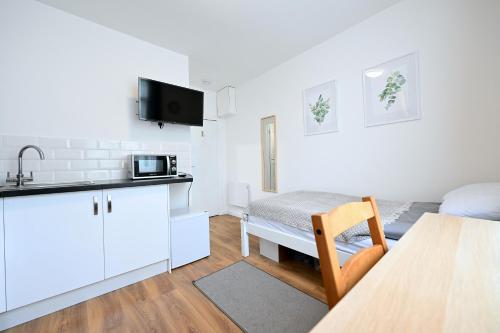 uma cozinha e sala de estar com uma mesa e um micro-ondas em Studio Apartment - London em Londres