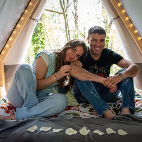 a man and a woman sitting on a bed at Tenda Tipì Glamping Verde Mare by SMART-HOME in Genova