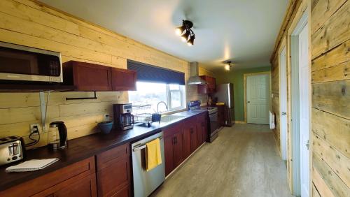 cocina con armarios de madera y encimera en Caribou Cottage, en Churchill