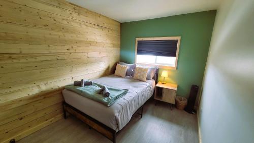 a small bedroom with a bed with a wooden wall at Caribou Cottage in Churchill