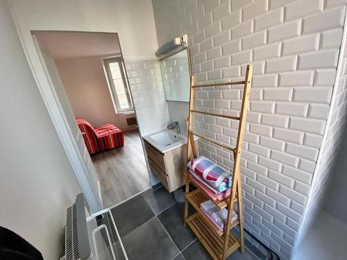 La salle de bains est pourvue d'un lavabo et d'un mur en briques blanches. dans l'établissement ARconciergerie Appartement hyper-centre, à Milly-la-Forêt