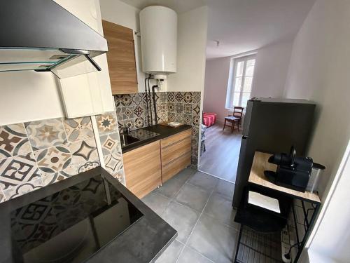 une cuisine avec un réfrigérateur noir et des armoires en bois dans l'établissement ARconciergerie Appartement hyper-centre, à Milly-la-Forêt