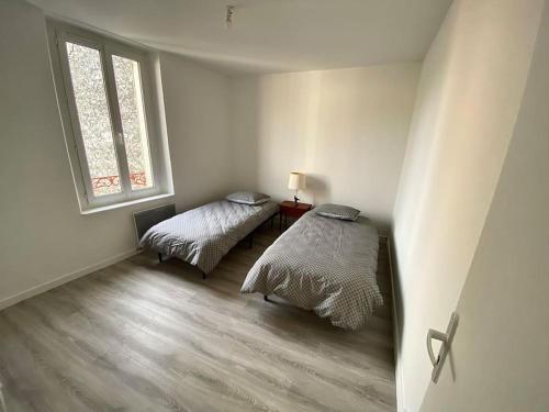 Cette chambre blanche dispose de deux lits et d'une fenêtre. dans l'établissement ARconciergerie Appartement hyper-centre, à Milly-la-Forêt