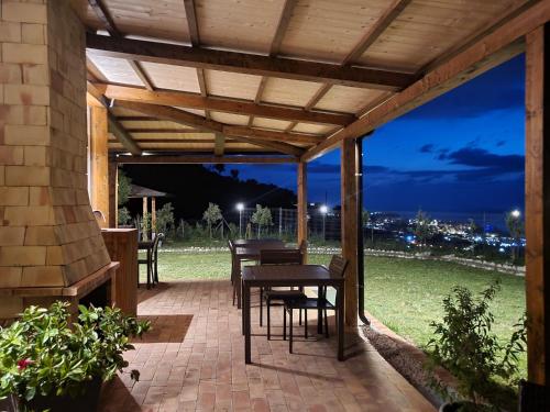 un patio con mesa y sillas bajo una pérgola en Casa Natura 40 en Parghelia