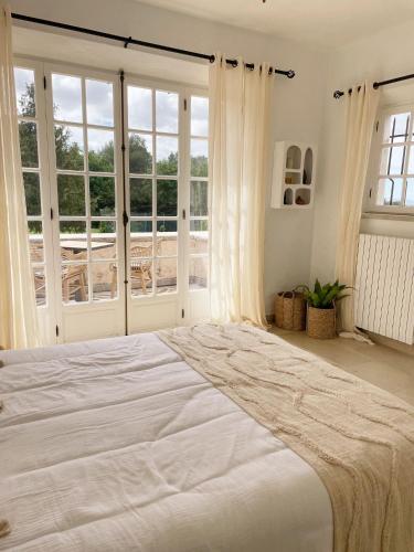 a large white bed in a room with windows at Le Mas Baïeta in Vence
