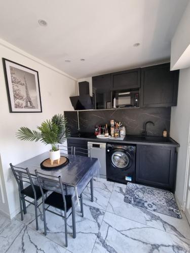 une cuisine avec des armoires noires et une table avec des chaises dans l'établissement T2 neuf centre ville Saint Raphaël avec terrasse et parking gratuit, prés de la plage et commerces!, à Saint-Raphaël