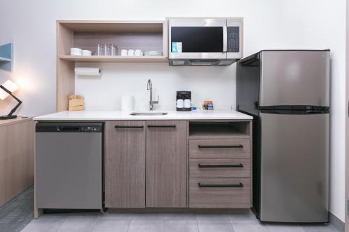 a small kitchen with a refrigerator and a sink at Home2 Suites By Hilton Huntsville, Tx in Huntsville