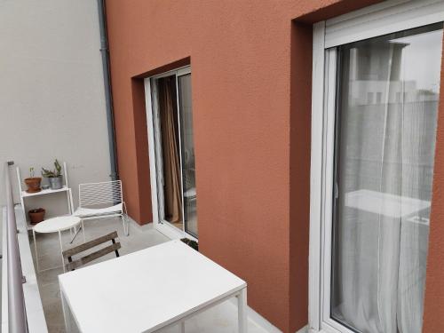 - un balcon avec une table et des chaises blanches à côté d'un bâtiment dans l'établissement La Tourterelle By Nid'Ouest, à Rennes