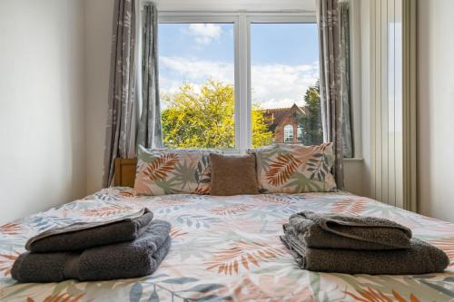 Modern 2 bedroom apartment in Mitcham, London في ميتشام: غرفة نوم بسرير مع نافذة كبيرة