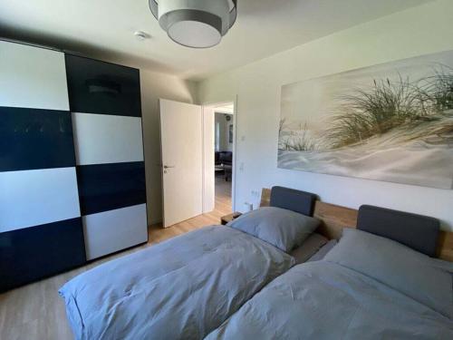 een slaapkamer met 2 bedden en een schilderij aan de muur bij Holiday home Ankerherz in Butjadingen