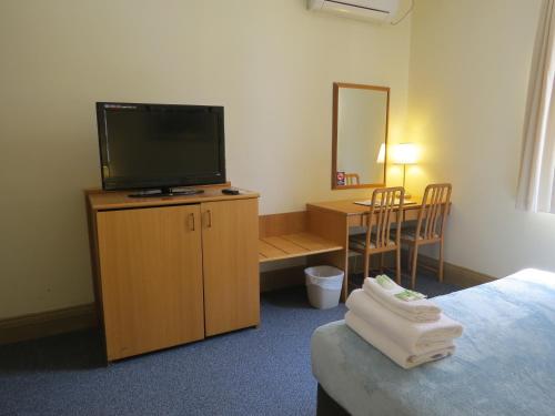 a hotel room with a television and a desk with a chair at Criterion Hotel Perth in Perth