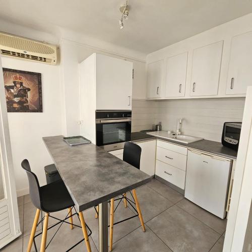 une cuisine avec des armoires blanches et une table et des chaises dans l'établissement Studio Cannes le Val D'or Chez Lisa, à Cannes