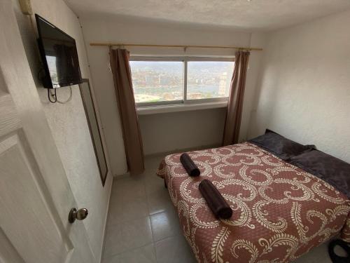 niewielka sypialnia z łóżkiem i oknem w obiekcie Sierra 1 w Acapulco