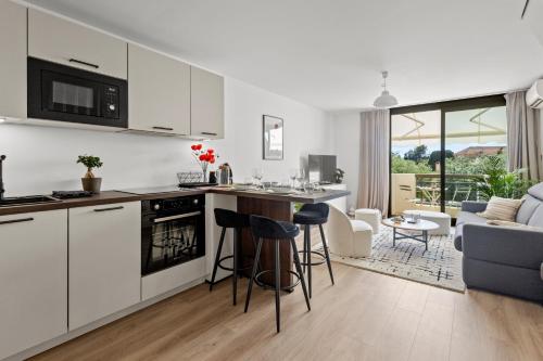 une cuisine avec des armoires blanches et un salon dans l'établissement Adorable 2P avec Piscine Cannes, à Cannes