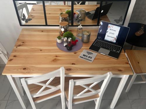 SIYAY Apartment في إيلات: طاولة خشبية فوقها جهاز كمبيوتر محمول