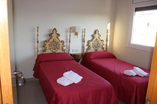 2 camas en una habitación con sábanas rojas en el turó en Sant Boi de Lluçanès