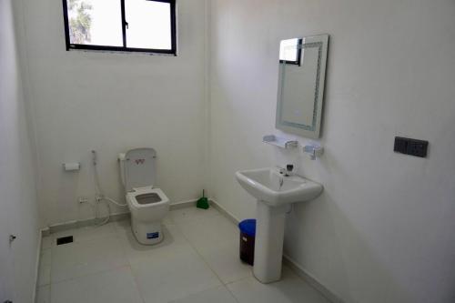 a white bathroom with a toilet and a sink at SHAKIN SHASHA BEACH HOUSE in Jaffna