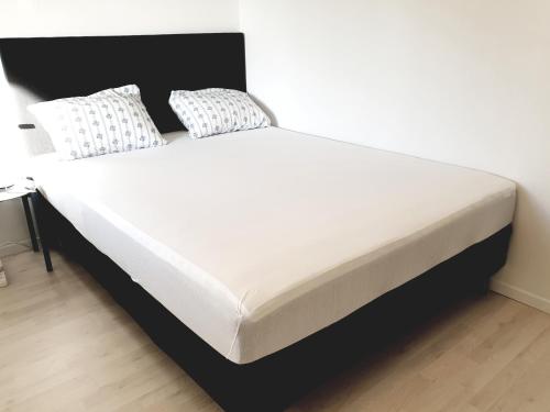 - un lit avec des draps et des oreillers blancs dans l'établissement Spacious 2 Bedroom Apartment in Arendal., à Arendal