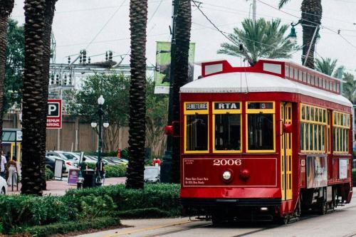 a red trolley car on a street with palm trees at Heart of the French Quarters in New Orleans