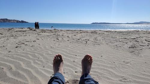 a person laying on a beach with their feet in the sand at Twin Brothers Pichidangui 1 in Pichidangui
