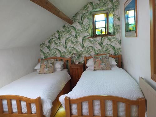 two twin beds in a small room with wallpaper at The Harbour in Evenjobb